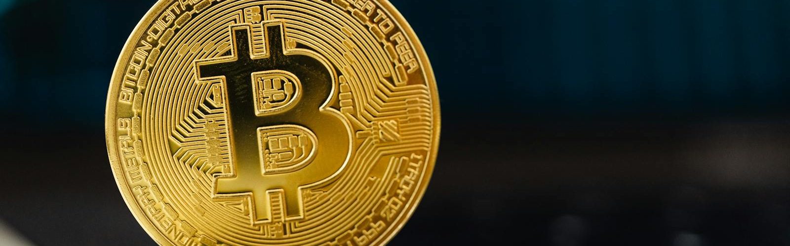 Golden Bitcoin coin standing upright on a laptop keyboard, representing digital currency.