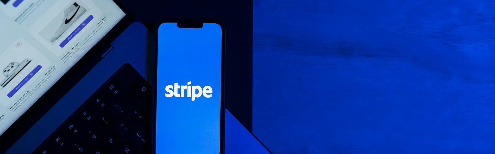 A smartphone displaying the Stripe app placed on a laptop keyboard with a blue monochromatic tone.