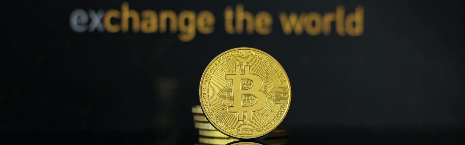 Close-up of a Bitcoin coin with Binance logo and text reflecting in dark surface.